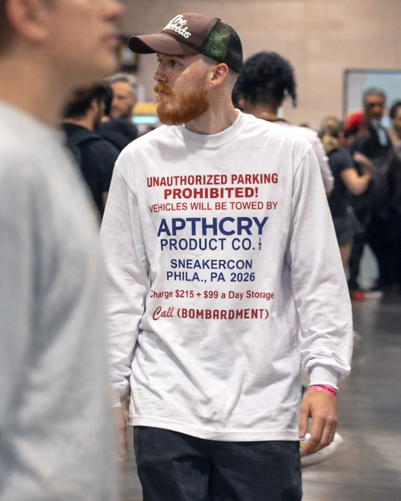 Man wearing a white sweatshirt with text at a sneaker convention