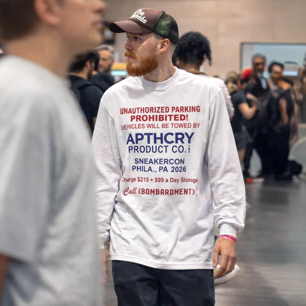 Man wearing a white sweatshirt with text at a sneaker convention